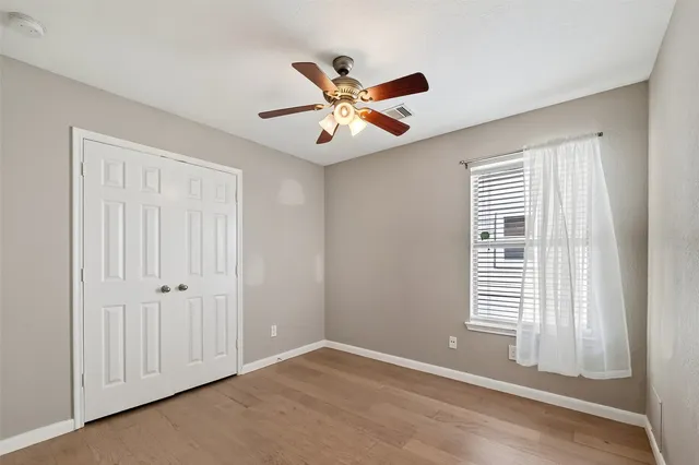 a view of an empty room with window and a chandelier fan