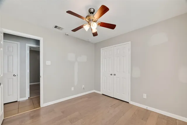 an empty room with ceiling fan and window