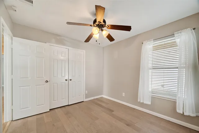 an empty room with windows and fan