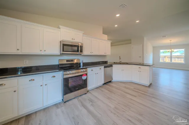 a kitchen with granite countertop white cabinets and white appliances