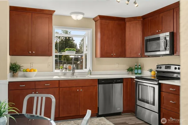 a kitchen with stainless steel appliances granite countertop wooden cabinets a stove top oven a sink and dishwasher