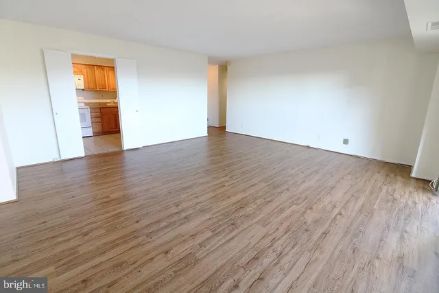 a view of an empty room with wooden floor and closet
