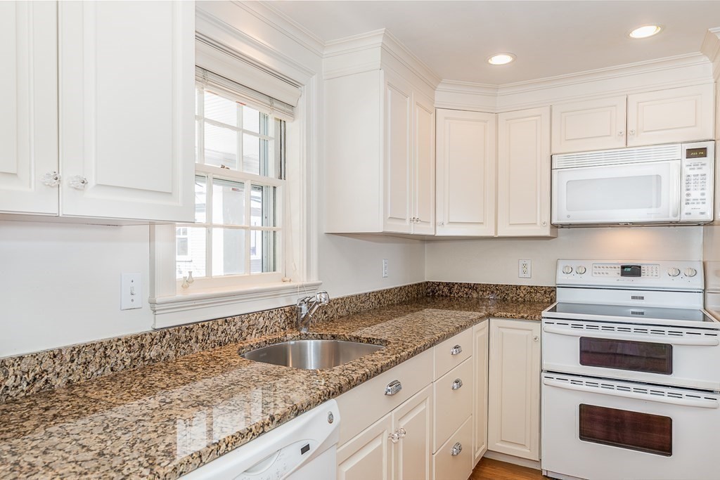 147 Front Street, Unit 6 Marblehead, MA 01945 - Photo 10 of 25 a kitchen with granite countertop white cabinets and white appliances