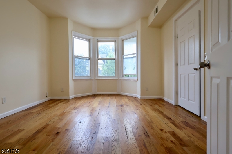 112 Chadwick Avenue, Unit 2 Newark, NJ 07108 - Photo 1 of 13 an empty room with wooden floor and windows