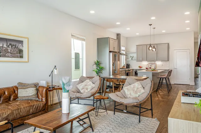a living room with furniture and a dining table with wooden floor