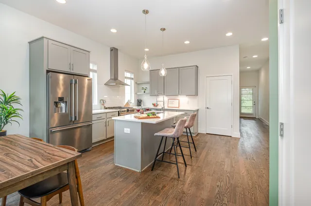 a kitchen with stainless steel appliances granite countertop a refrigerator a sink dishwasher a stove and a refrigerator with wooden floor