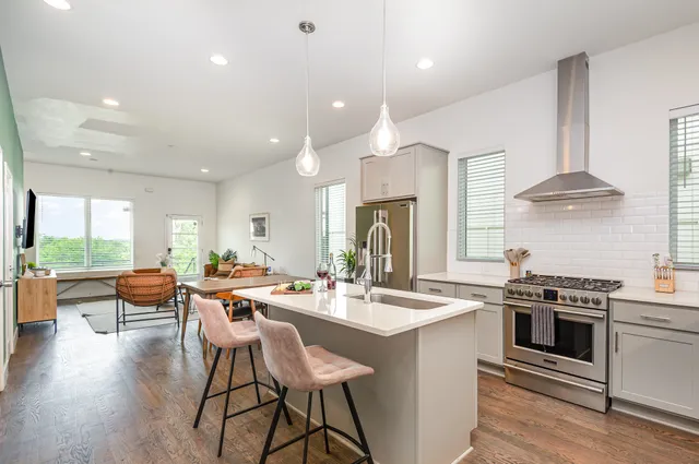 a kitchen with stainless steel appliances a stove a sink a oven a dining table and chairs