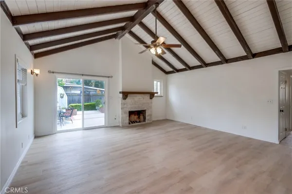 a view of an empty room with wooden floor fireplace and a window