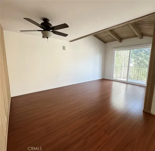 a view of a big room with wooden floor a ceiling fan and windows