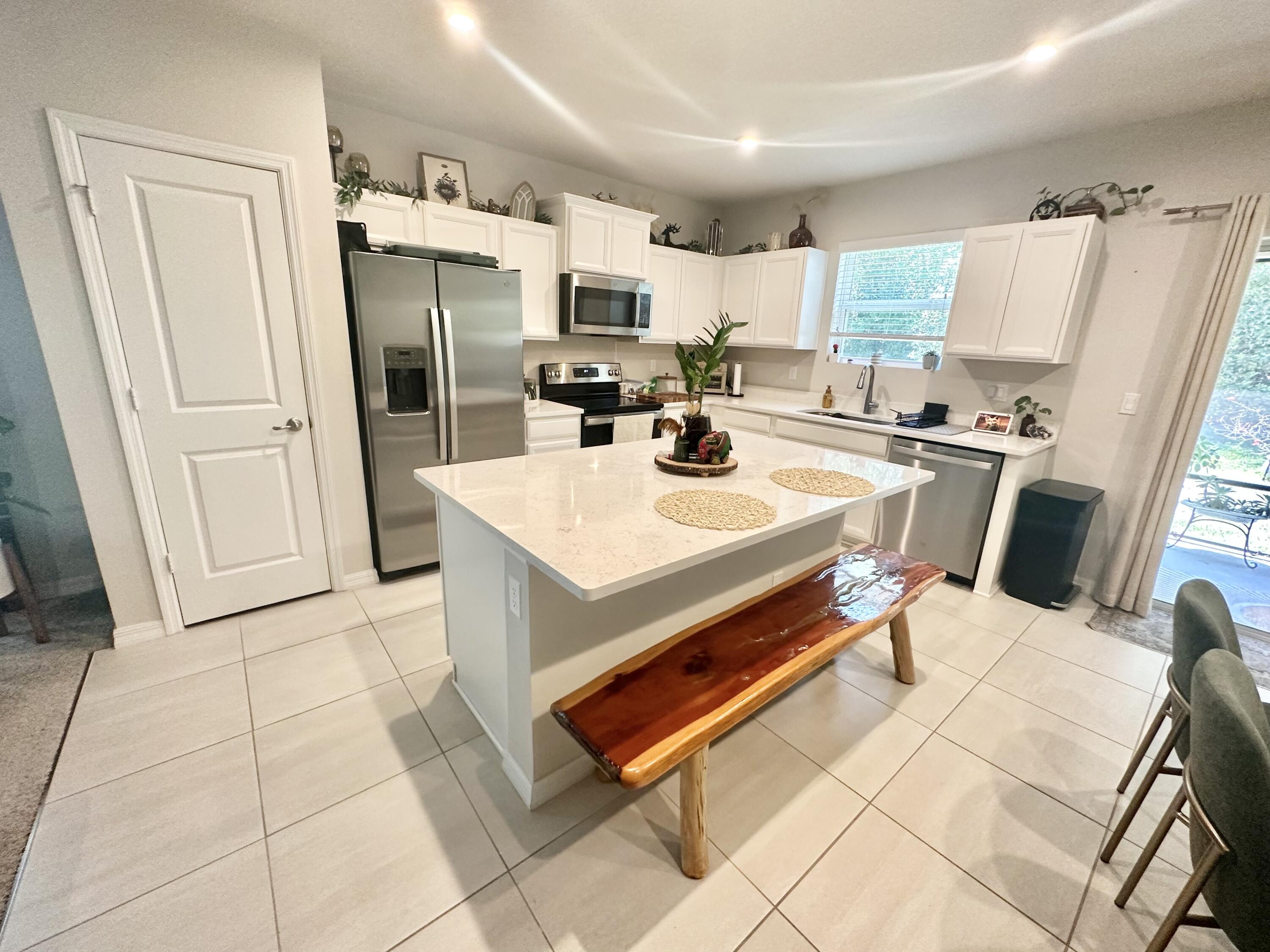 a kitchen with stainless steel appliances a refrigerator a stove a sink dishwasher and white cabinets with wooden floor