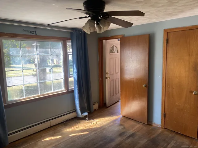 an empty room with wooden floor fireplace and windows