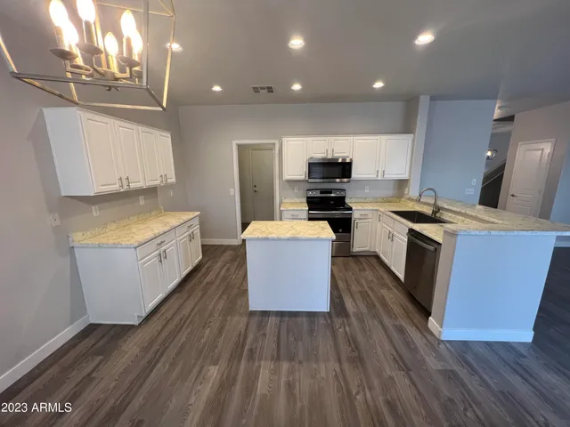 a kitchen with stainless steel appliances a stove top oven a sink dishwasher and a refrigerator with wooden floor