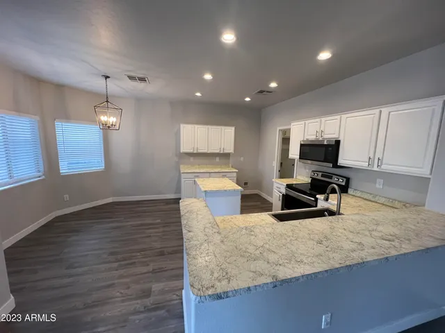 a kitchen with granite countertop a stove a sink and a microwave
