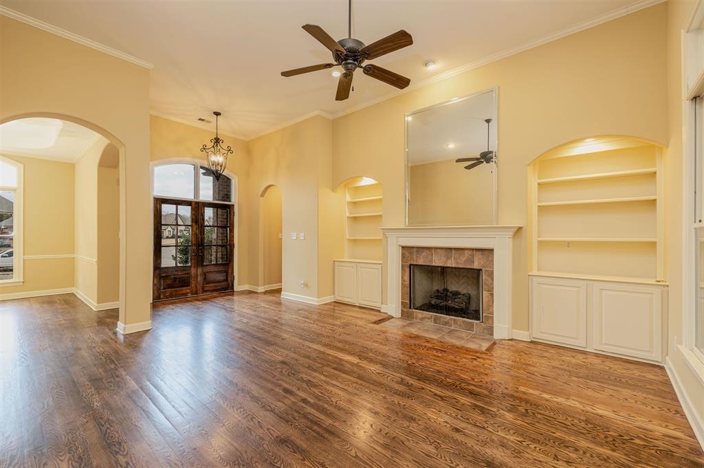 5380 Scarlet Ridge Drive Arlington, TN 38002 - Photo 9 of 35 Spacious living area featuring rich wood-finish flooring, a tile-surround fireplace with a white mantel, and built-in shelving with lower cabinetry