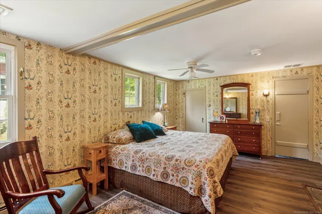 a bedroom with a bed dresser and a wooden floor