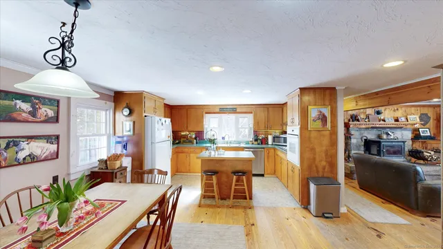 a kitchen with a refrigerator a stove top oven a sink dishwasher and couches with wooden floor