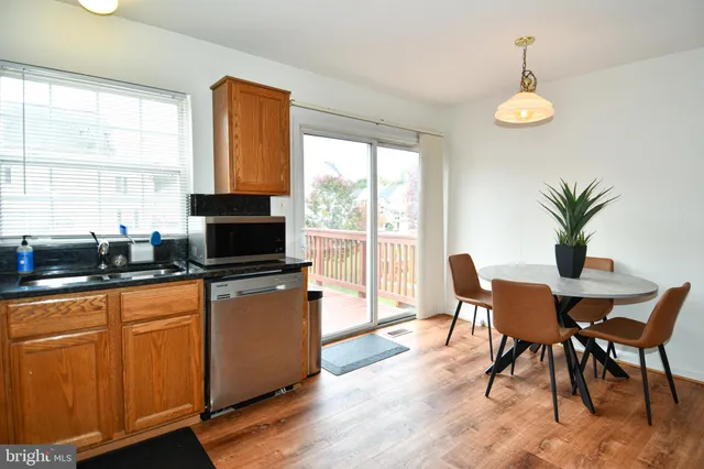 a kitchen with stainless steel appliances granite countertop a stove top oven a sink a dining table and chairs with wooden floor