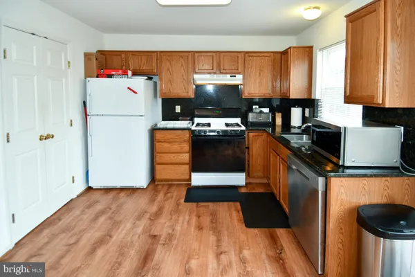 a kitchen with stainless steel appliances granite countertop a refrigerator stove top oven and sink