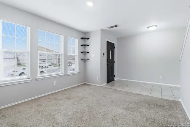 an empty room with windows and fan