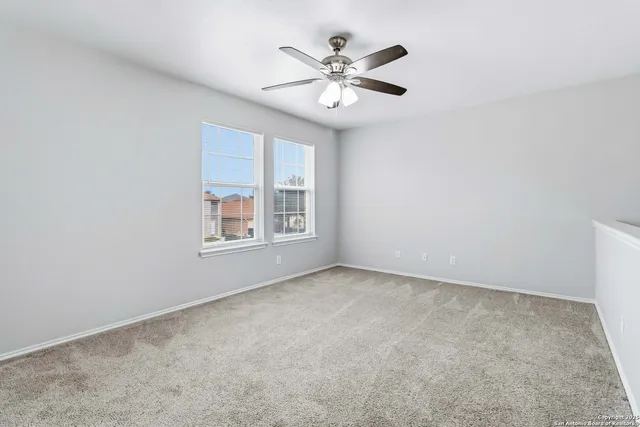 an empty room with windows and ceiling fan