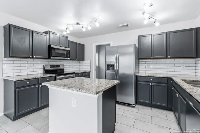 a kitchen with kitchen island granite countertop a sink counter top space and stainless steel appliances