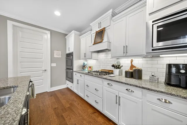 a kitchen with granite countertop cabinets stainless steel appliances and wooden floor