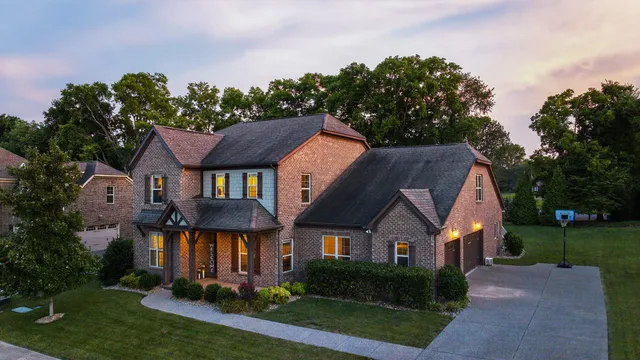a aerial view of a house next to a big yard and large tree