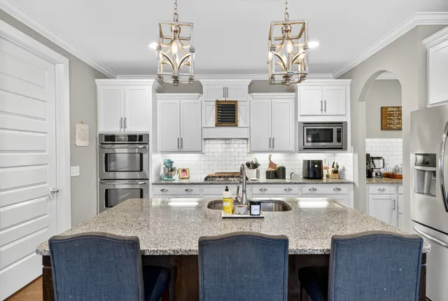 a kitchen with stainless steel appliances granite countertop a sink dishwasher stove refrigerator and microwave with wooden floor