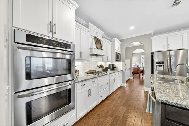 a kitchen with stainless steel appliances white cabinets a stove a sink and a refrigerator
