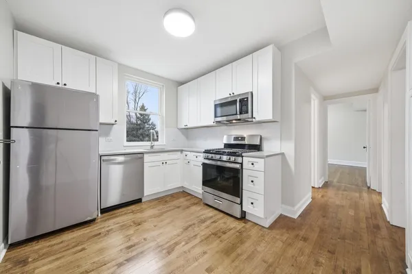 a kitchen with refrigerator a sink and wooden floor