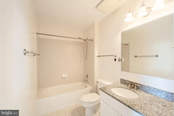 a bathroom with a granite countertop sink a toilet and shower