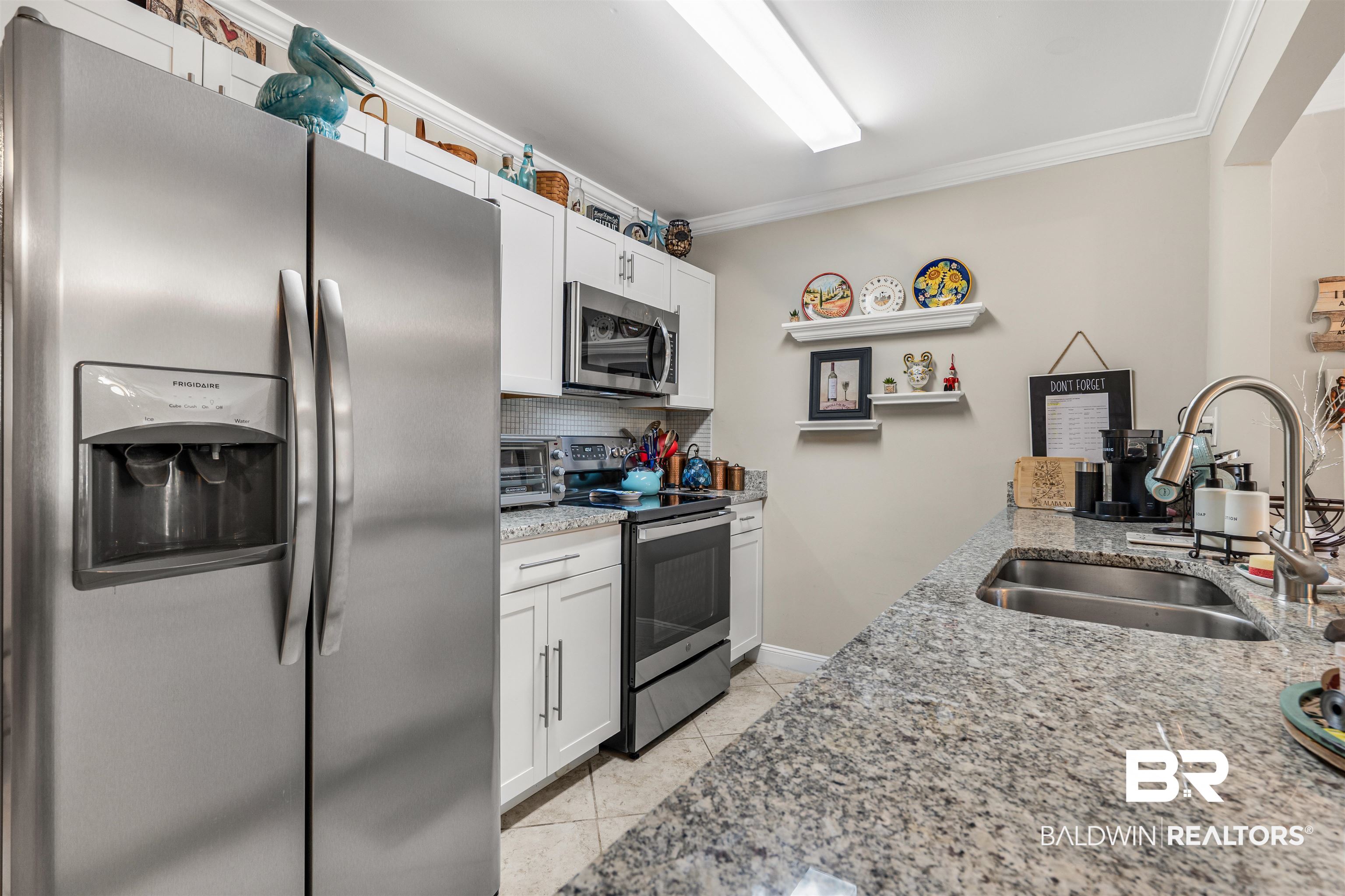 1517 Regency Road, Unit 68 Gulf Shores, AL 36542 - Photo 15 of 43 Kitchen featuring appliances with stainless steel finishes, crown molding, sink, light tile patterned floors, and white cabinets