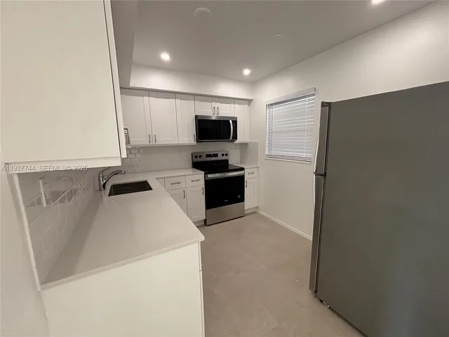 a view of kitchen with refrigerator stove microwave and cabinets