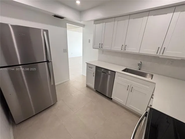 a kitchen with stainless steel appliances a refrigerator a sink and cabinets