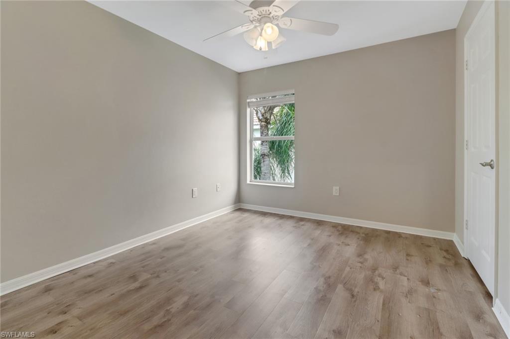 815 Hampton Circle, Unit 143 Naples, FL 34105 - Photo 28 of 30 an empty room with wooden floor chandelier fan and windows