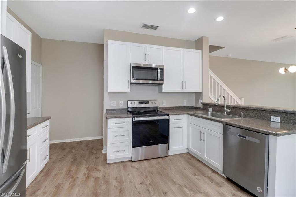 815 Hampton Circle, Unit 143 Naples, FL 34105 - Photo 5 of 30 a kitchen with stainless steel appliances granite countertop a stove a sink and a refrigerator