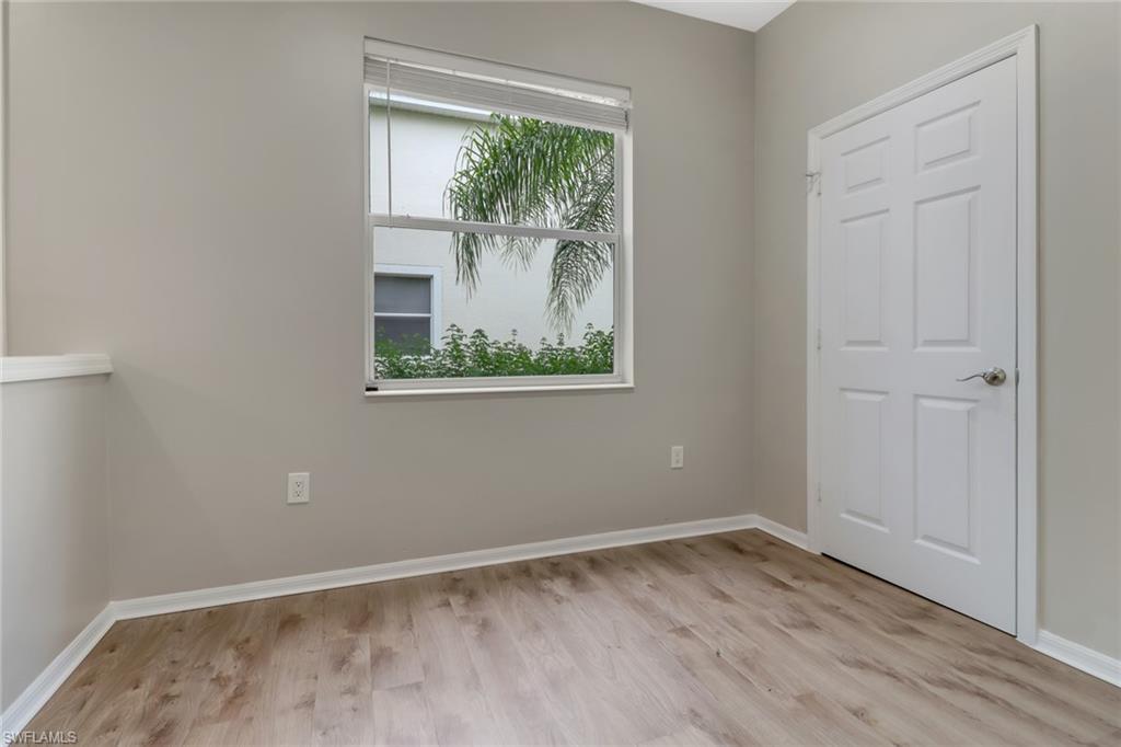 815 Hampton Circle, Unit 143 Naples, FL 34105 - Photo 7 of 30 a view of an empty room with wooden floor and a window