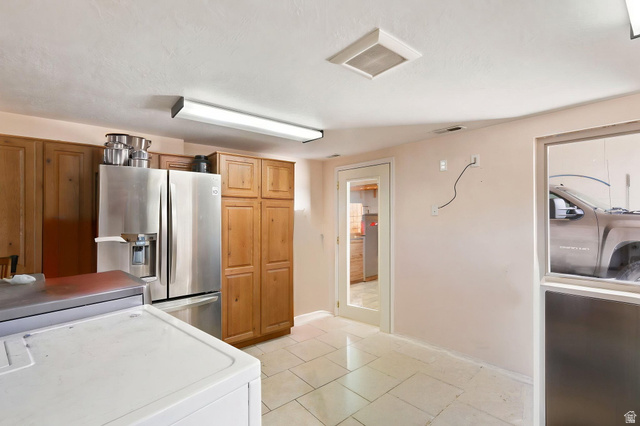 580 North 300 East Logan, UT 84321 - Photo 68 of 74 Kitchen area featuring wood cabinetry, stainless steel refrigerator, and tile flooring