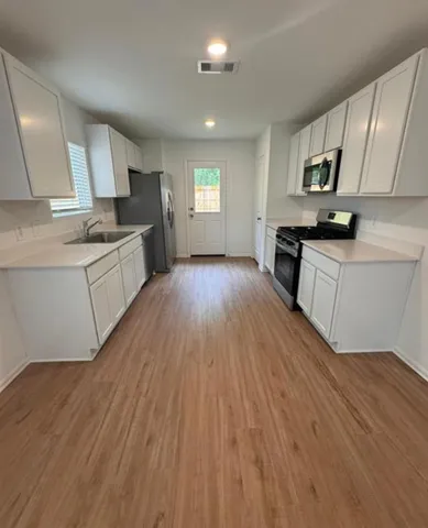 a large kitchen with cabinets wooden floor and stainless steel appliances