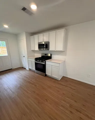 a view of kitchen with wooden floor and electronic appliances