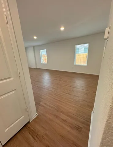 an empty room with wooden floor and windows