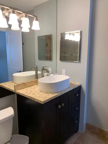 a bathroom with a granite countertop sink and a mirror with toilet