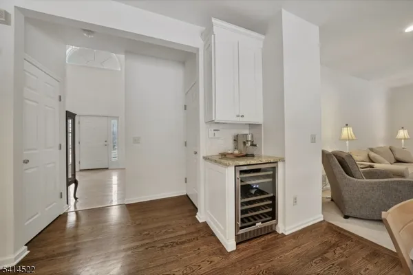 a view of kitchen and empty room with wooden floor