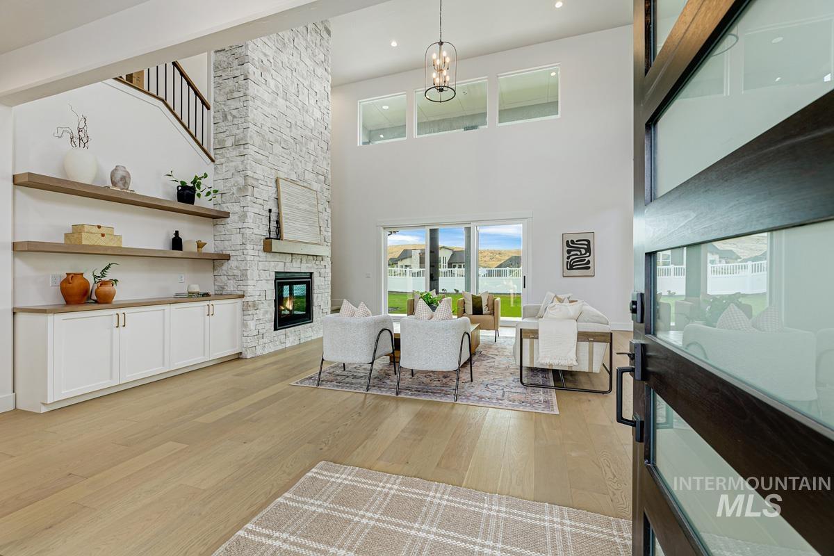 13339 North Hazel Grouse Way Boise, ID 83714 - Photo 4 of 50 Living area with light wood-style floors, a stone fireplace, a high ceiling, and suspended lighting