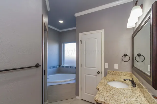 a bathroom with a granite countertop tub sink and mirror