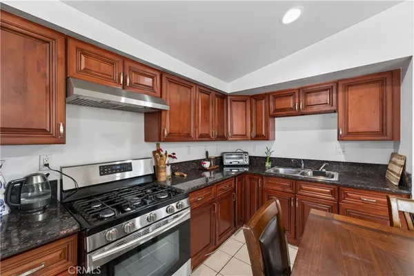 a kitchen with granite countertop stove top oven sink and cabinets