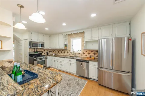 a kitchen with kitchen island granite countertop stainless steel appliances and wooden cabinets