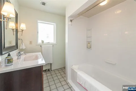a bathroom with a sink a tub and a mirror