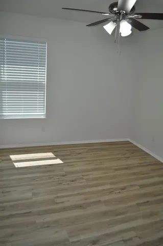 a view of empty room with wooden floor and fan