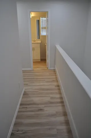 a view of a hallway with wooden floor and a bathroom